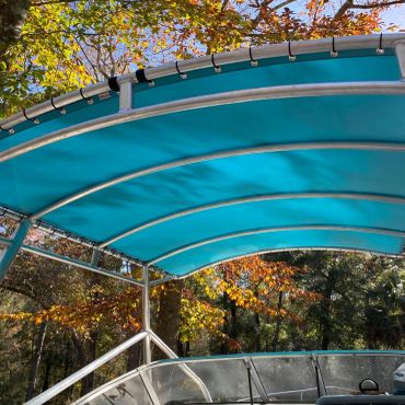 Blue canopy over a boat with autumn trees in the background.