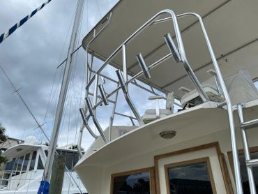 Close-up of a yacht's metal railing and fishing rod holders against a cloudy sky.