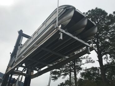 A pontoon boat elevated on a hydraulic lift outdoors.